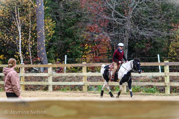 a person riding a horse next to a fence