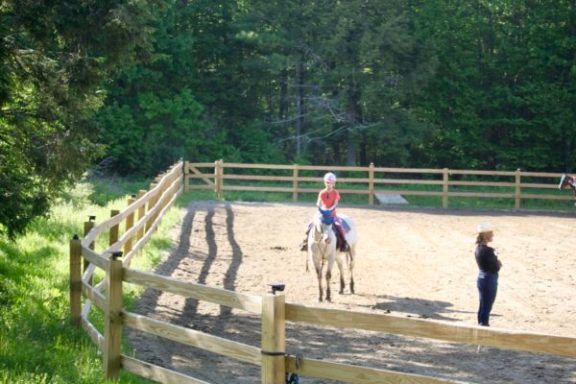 a person riding a horse next to a fence