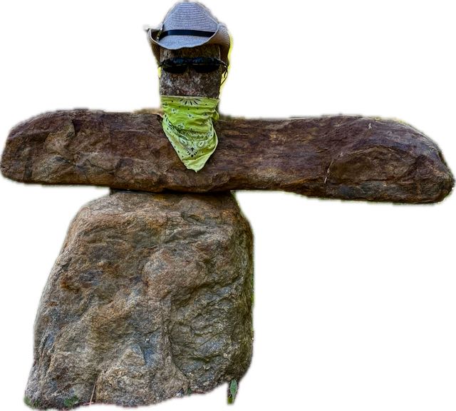 Stacked rocks resembling a person wearing a hat, sunglasses, and green bandana.